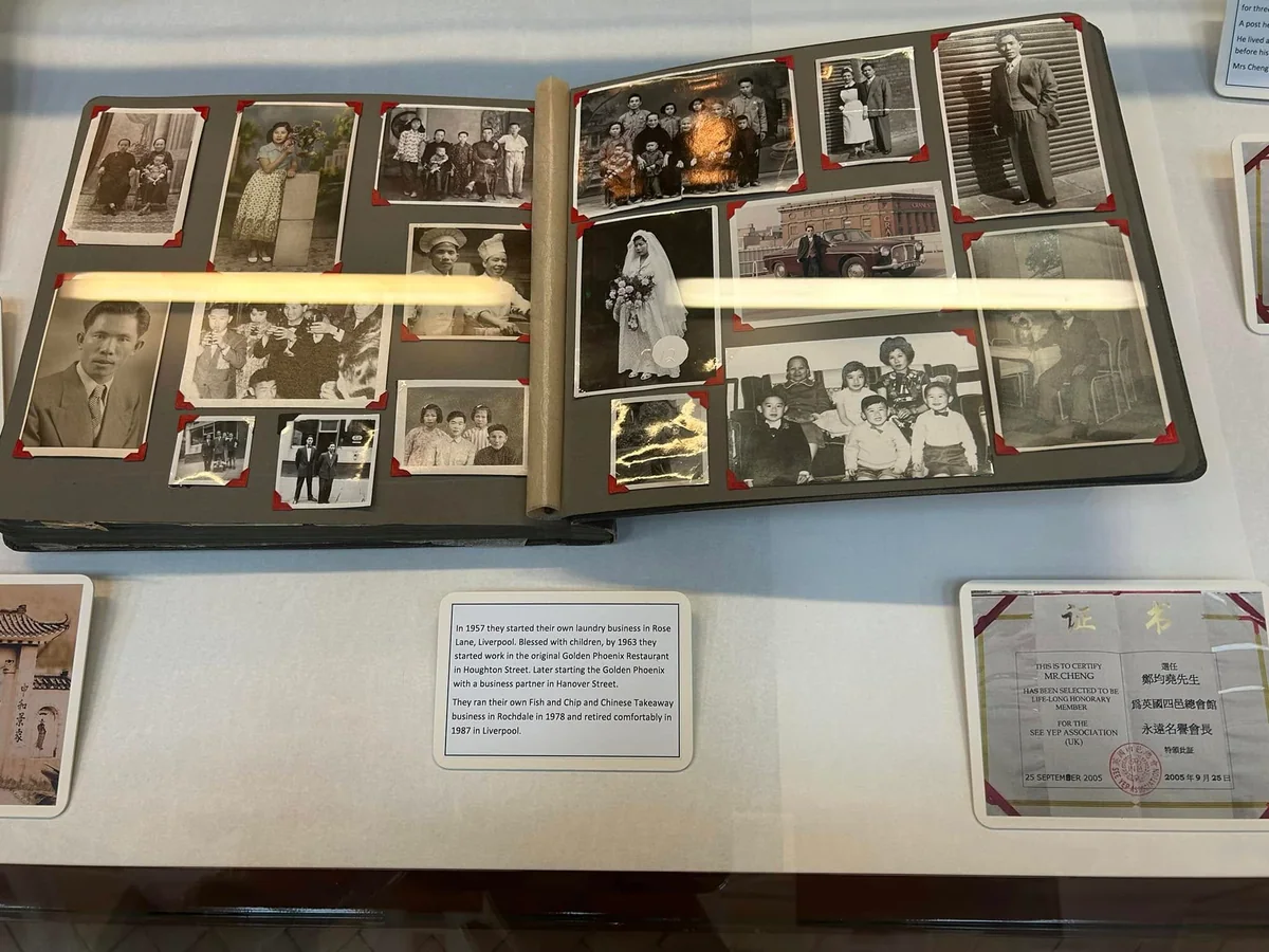 An open album of family photographs displayed in a glass case.