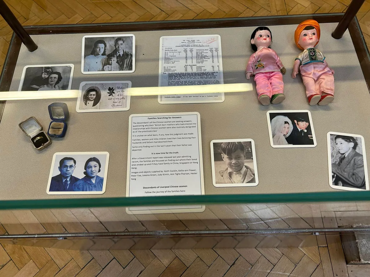 An exhibition case containing dolls, rings, documents and family photographs.